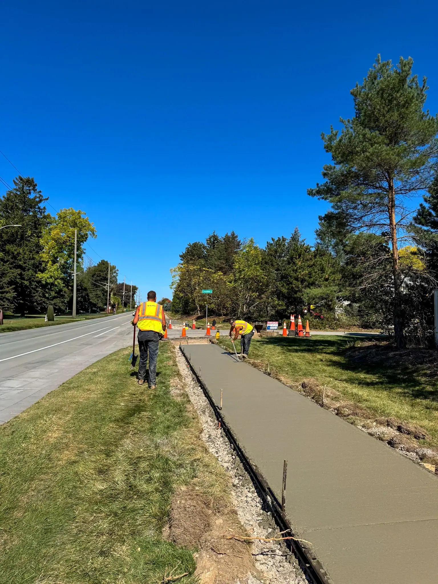 Crews pouring and finishing fresh concrete for new sidewalks along Five Mile Line Road in Penfield NY under Costich Engineering’s design.