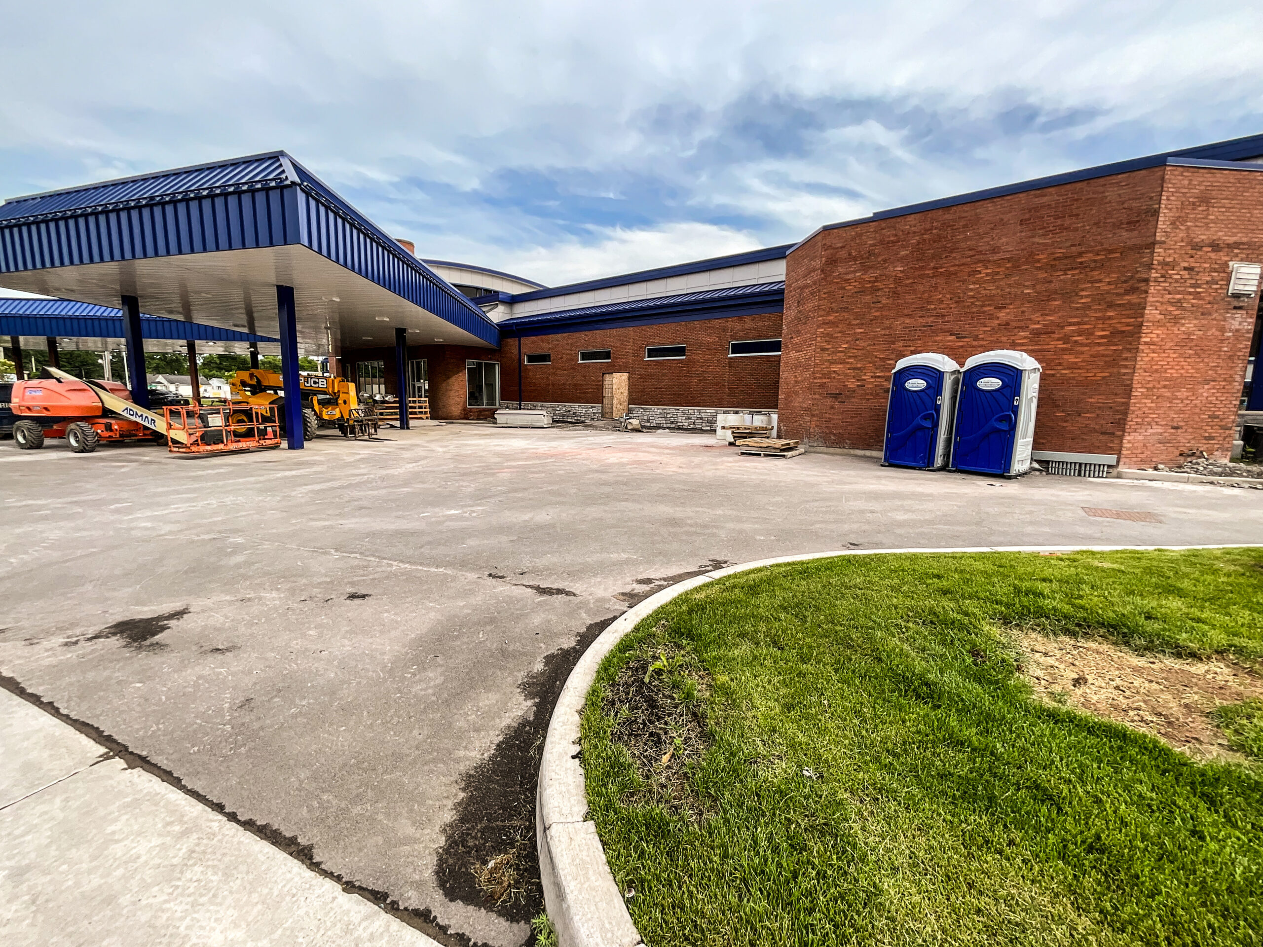 Delta Sonic West Henrietta parking areas closed for site redesign, showing finished concrete paving work, building construction, and concrete edging for improved traffic flow.