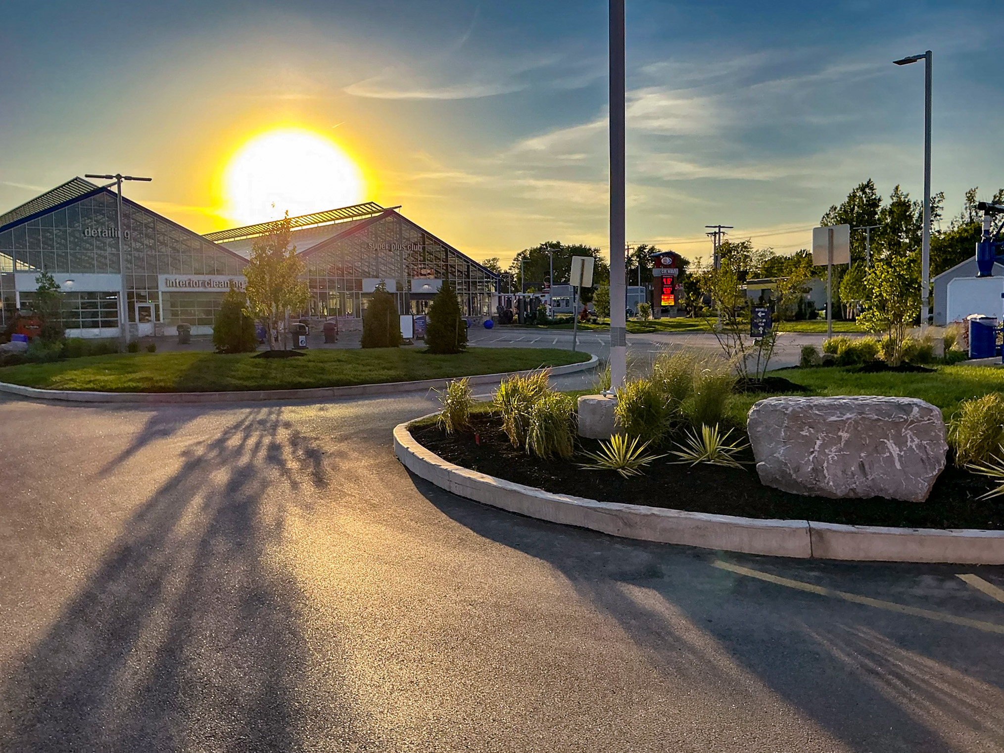 Delta Sonic West Henrietta carwash facility showing redesigned circulation, landscape plantings with ornamental grasses, and improved sight lines at sunset.
